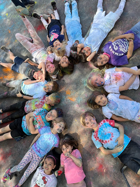Wild Roots students celebrating with color powder, lying in a circle